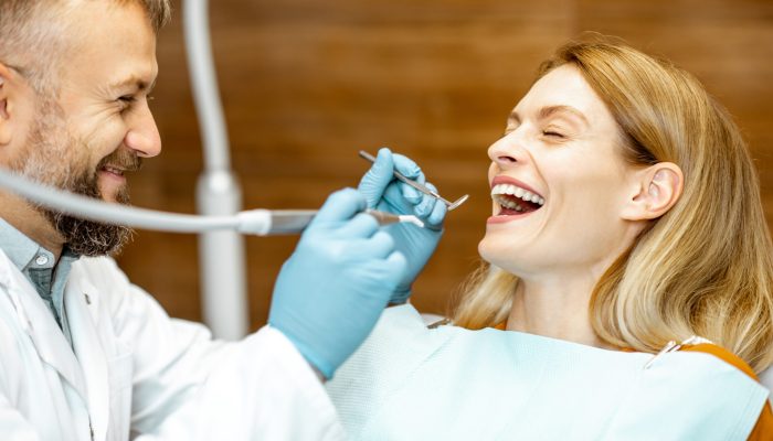 Beautiful woman as a patient with senior dentist smiling and feeling trust during a medical consultation at the dental office